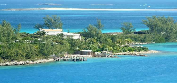 Bahamas Sandstrand - dahinter grüne saftige Stäucher und ein Apartment