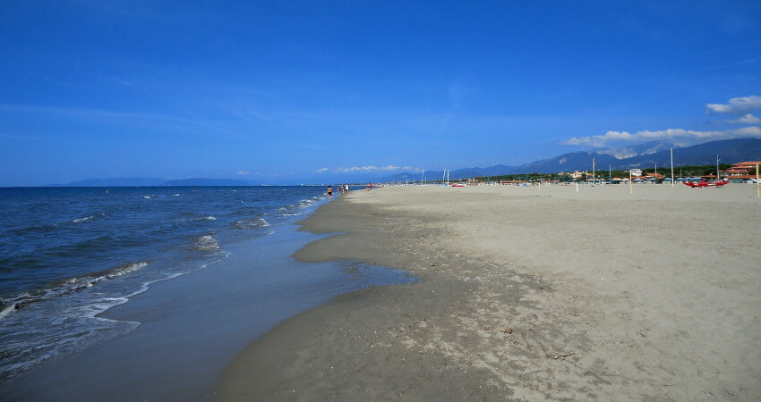 Sandstrand mit klarem Wasser und fast wolkenlosem Himmel.