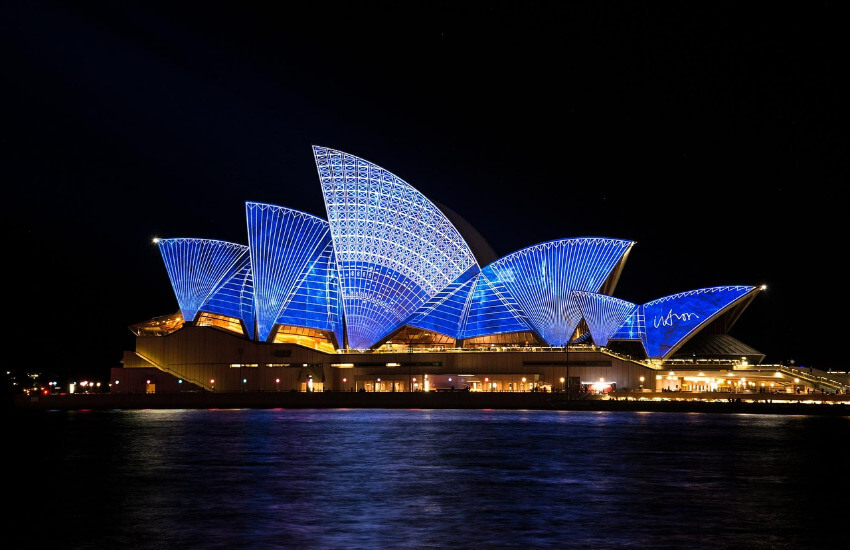 Das Opernhaus von Sydney in der Nacht mit einem kräftigen Blau beleuchtet.