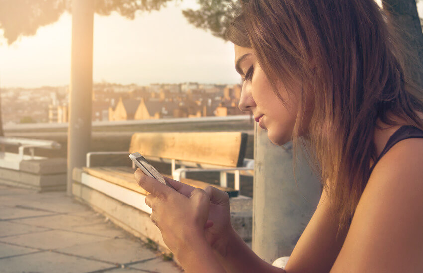 Eine junge Frau chattet mit Ihrem Smartphone.