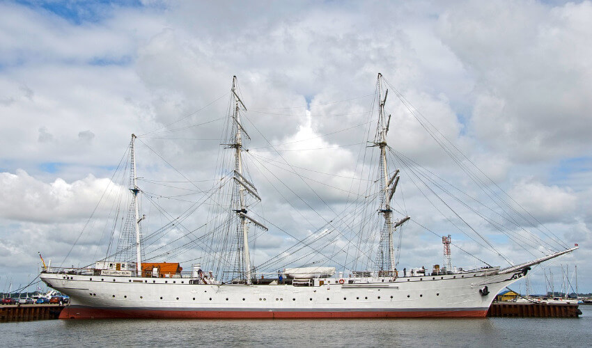 Ein weißes Segelschiff mit 3 hohen Masten.