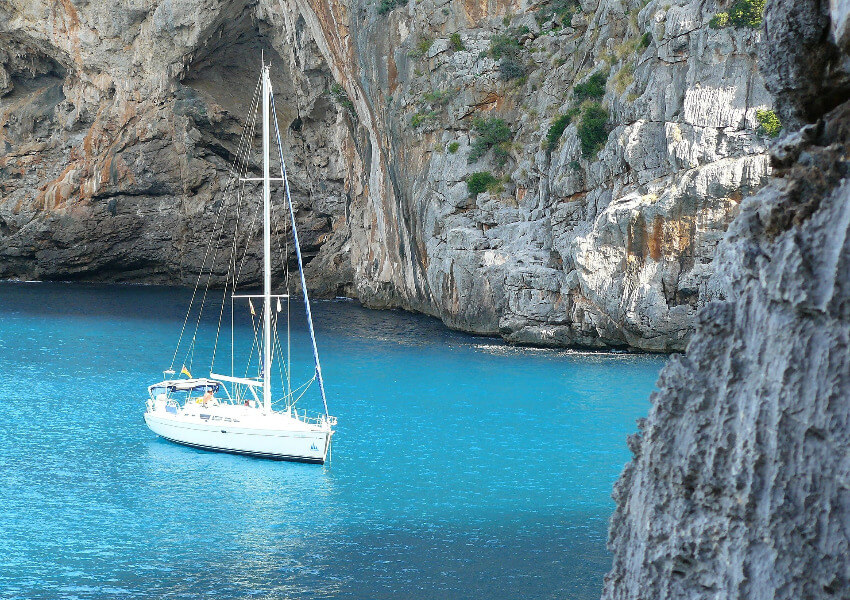 Ein Segelschiff ankert zwischen steilen Felswänden auf türkisem Meer.