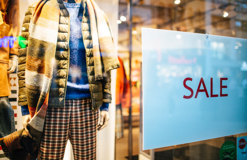 Eine Schaufensterpuppe mit Winterklamotten bekleidet und einem Sale Schild im Schaufenster.