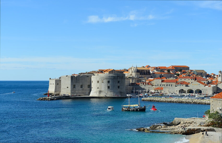 Die mittelalterliche Stadt Dubrovnik direkt am Meer unter blauem Himmel.
