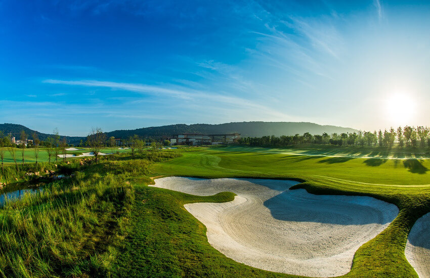 Golfplatz mit mehreren Sandbunkern unter strahlenden Sonnenschein.