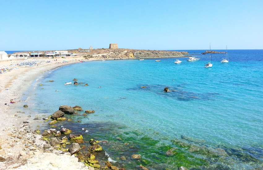 Eine kleine karge Insel mit einem kleinen Dorf und steinigen Strand.