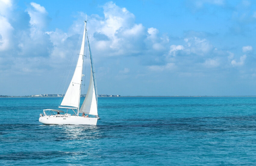 Ein weißes Segelboot im blau-türkisen Meer an einem schönen Sommertag.
