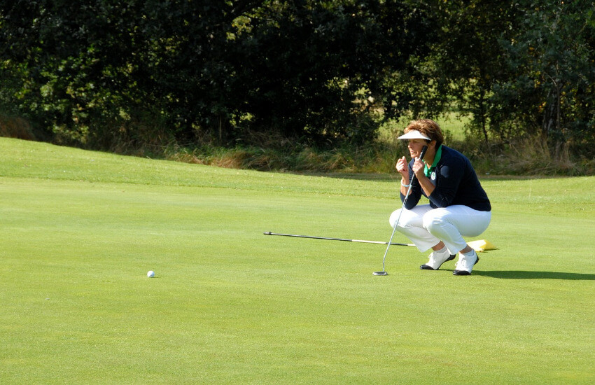 Eine Golfspielerin begutachtet das Gelände des Spielfeldes, um sich auf den nächsten Schlag vorzubereiten.