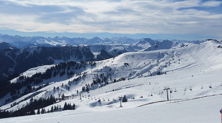 Eine verschneite Winterlandschaft mit Bergen, Skiliften und Skipisten.