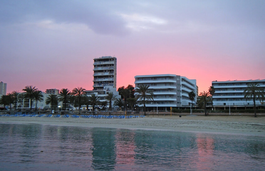 Weiße Hotels entlang eines Strandes bei Sonnenuntergang.