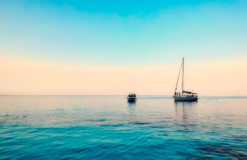 Ein Segelboot auf dem Meer unter Sonnenaufgang.