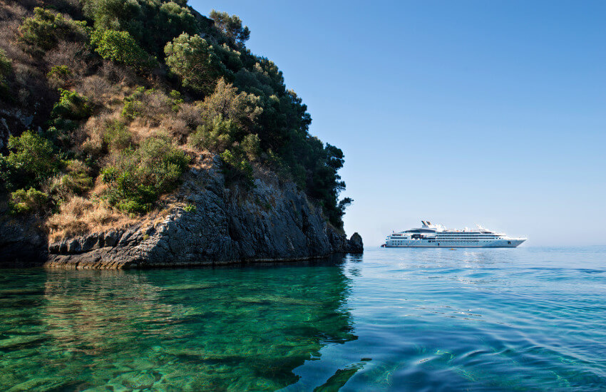 Ein kleines weißes Luxuskreuzfahrschiff nahe einer Bucht.