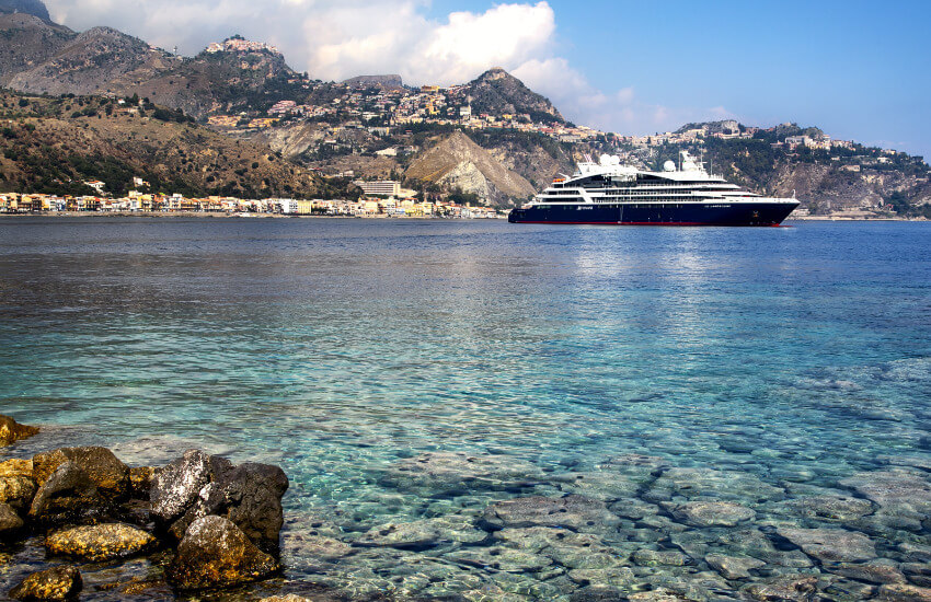 Ein kleines weißes-schwarzes Luxuskreuzfahrschiff nahe einer Bucht.