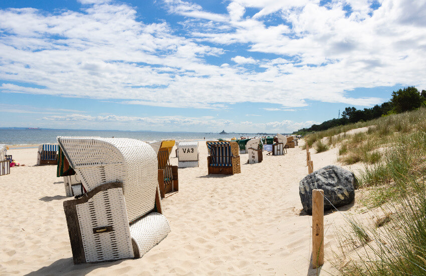 Einige Strandkörbe stehen kreuz und quer an einem Stand an der Ostsee.