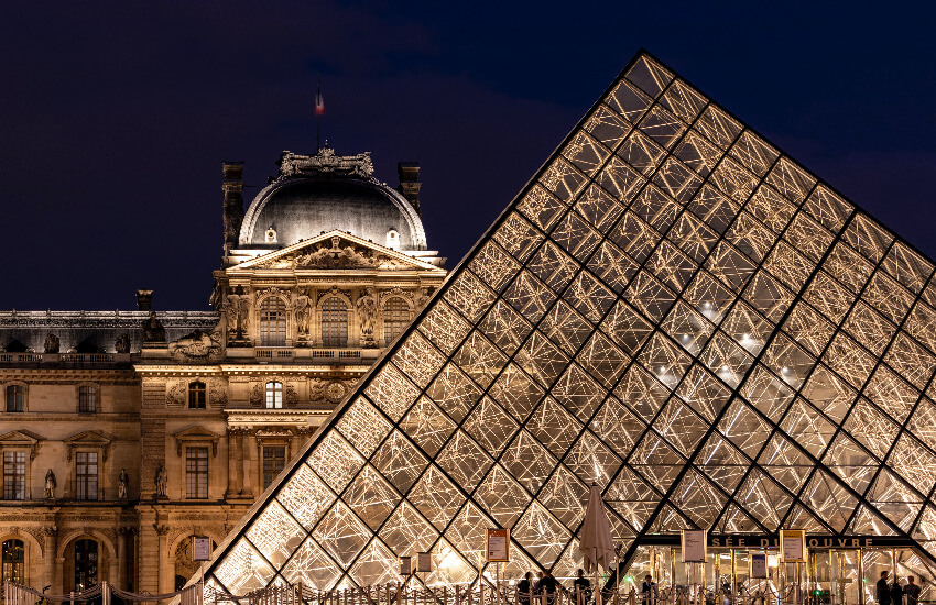 Eine beleuchtete Glaspyramide bei Nacht beim Louvre Paris