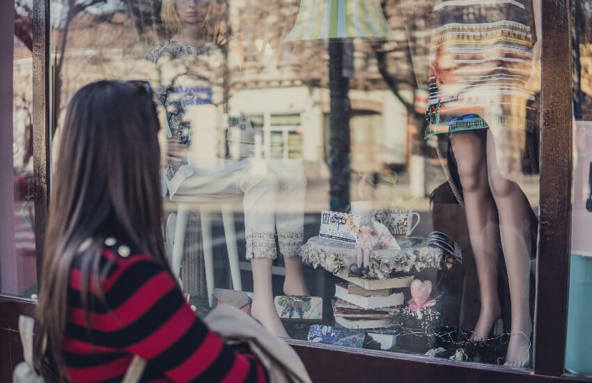 Eine Frau schaut in ein Schaufenster, wo Mode ausgestellt ist.