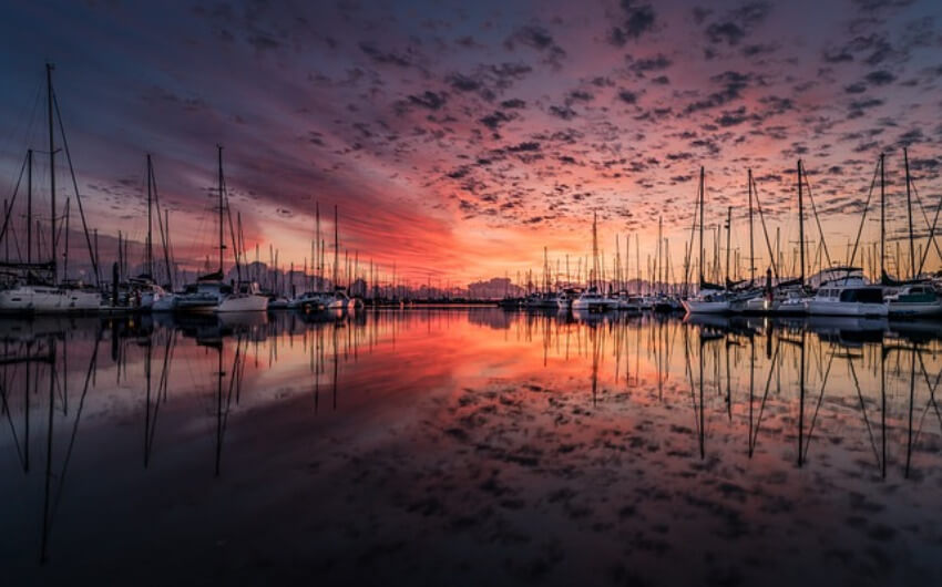 Yachthafen während des Sonnenaufgangs mit einem Himmel mit vielen rot und orange tönen.