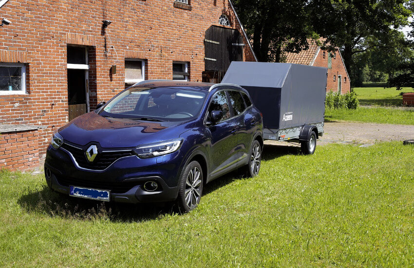 Ein dunkelblauer Renault mit einem Hänger mit Planenabdeckung.