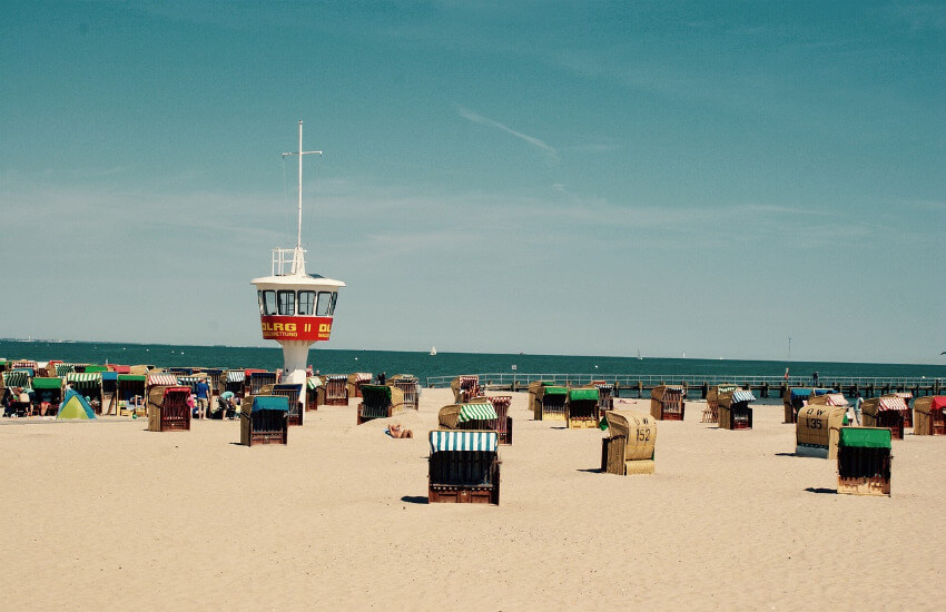 Viele Strandkörbe kreuz und quer verteilt auf einem breiten Sandstrand.