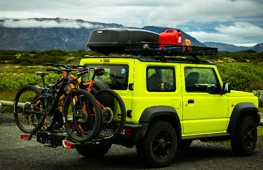 Ein neongelber Jeep mit einem Fahrradträger und einer Dachbox.