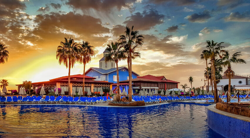 Ein Pool auf Teneriffa mit vielen blauen Liegestühlen rundum.