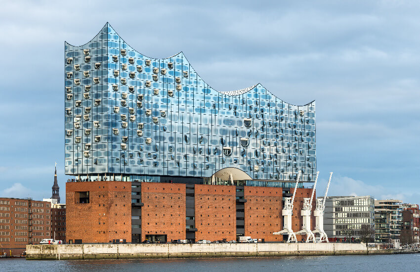 Blick vom Hamburger Hafen auf die imposante Elbphilharmonie, mit der wellenartigen Glasstruktur über dem dunklen Backsteinsockel.
