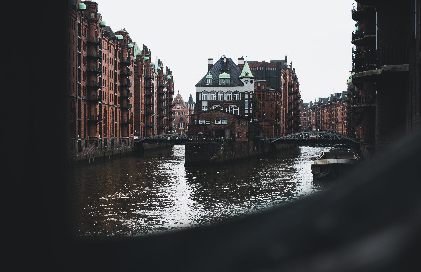 Historische Backsteingebäude der Hamburger Speicherstadt am Abend, deren Fassaden sich im Wasser eines Fleets spiegeln