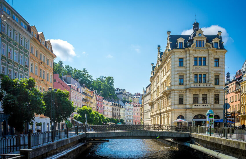 Historische Altstadt an einem Fluss in Tschechien mit Brücke und bunten Häusern.